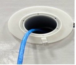 Blue cable inserted into a white circular port on a gray surface.