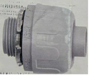 Close-up of a worn, rusted mechanical pipe fitting with a gray plastic grip.