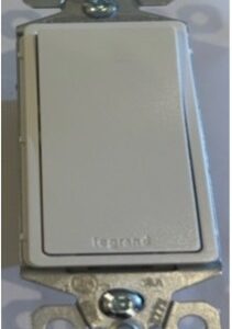 Close-up of a white electrical switch with the brand name 'Legrand'.