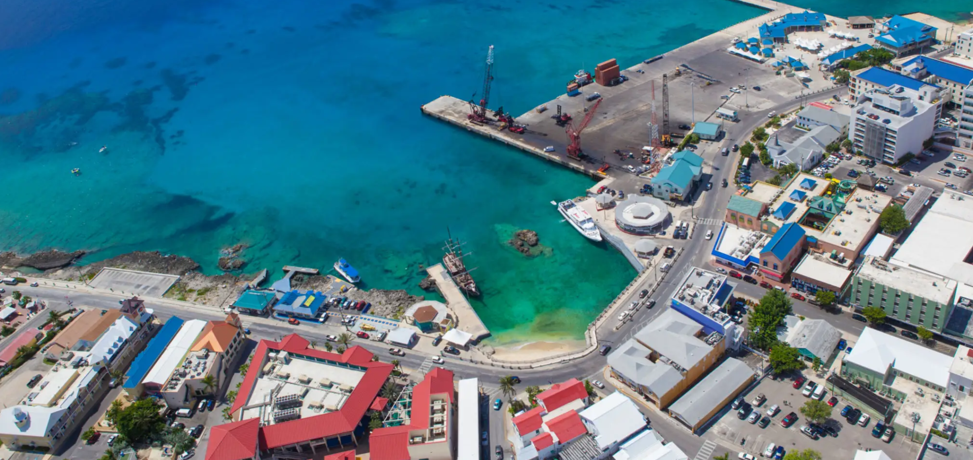 Aerial view of a vibrant coastal harbor with boats and colorful buildings.