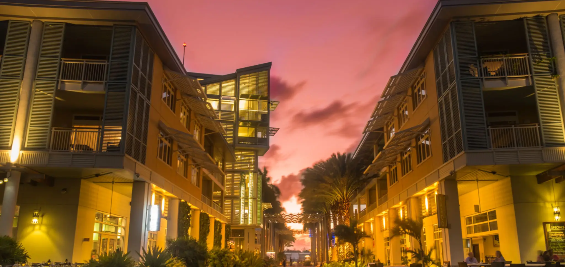 Modern residential buildings illuminated at sunset with a vibrant pink sky.
