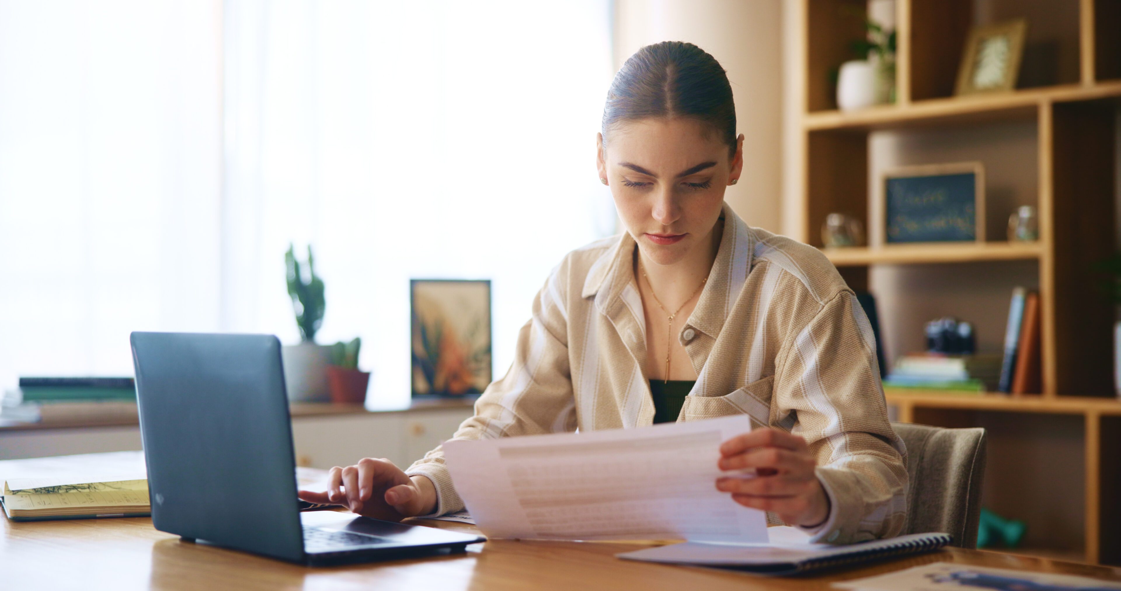 A woman reviewing documents at a desk in a cozy room.