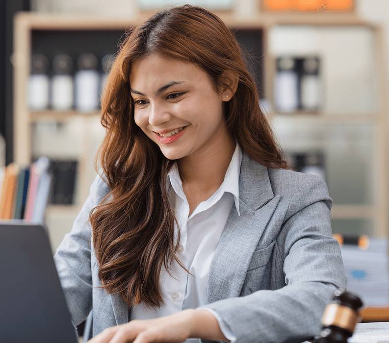 A confident businesswoman smiling while working on a laptop.
