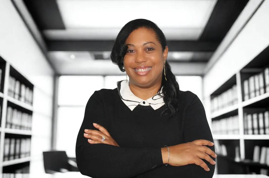 Confident woman smiling with arms crossed in a bright office space.