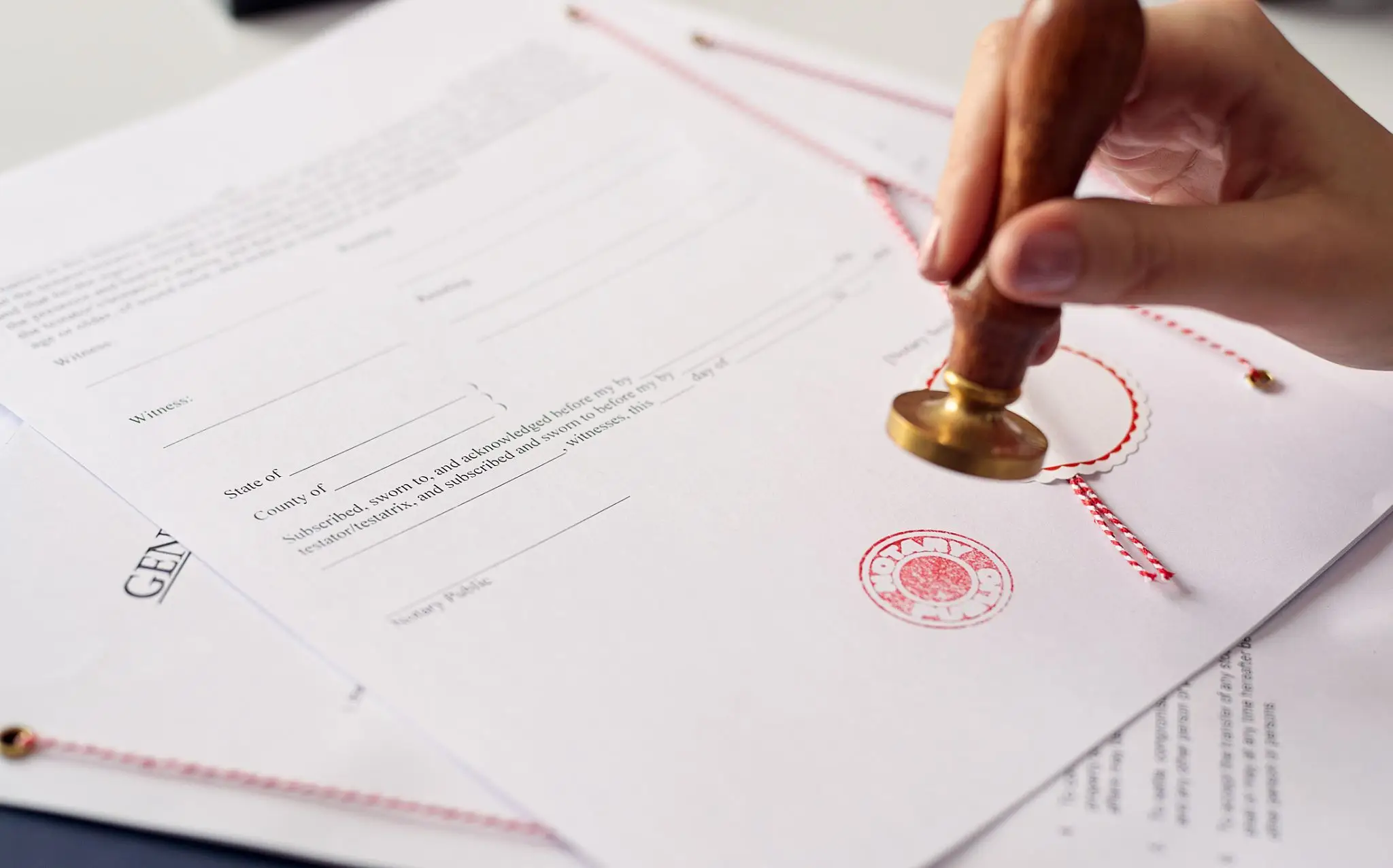 Hand stamping official documents with a red seal.